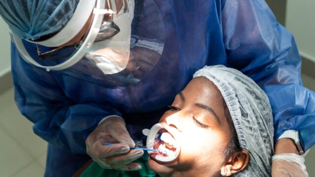 African Patient receiving whitening treatment by dentist