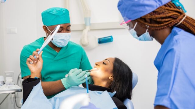 A patient looks at her teeth through the mirror, dental visit